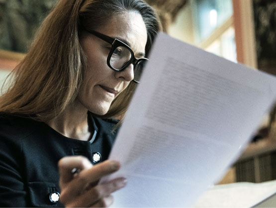 A woman wearing glasses and looking through documents